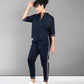 Woman in the Accented Set—a navy blue cotton co-ord with white stripes—paired with white sneakers, stands against a gray background.