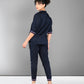 A woman in the Accented Set, a navy blue cotton co-ord, stands facing away and turns her head toward the camera, paired with white sneakers.