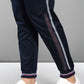 Wearing the Accented Set—navy striped track pants and a matching batwing sleeve shirt—a person pairs it with white sneakers, standing against a gray background.