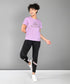 Woman in activewear smiling, wearing a Pilates Pink T-shirt, black leggings, and white sneakers.