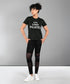 Person wearing a Pilates Black T-shirt and leggings stands with hands on hips against a plain background.