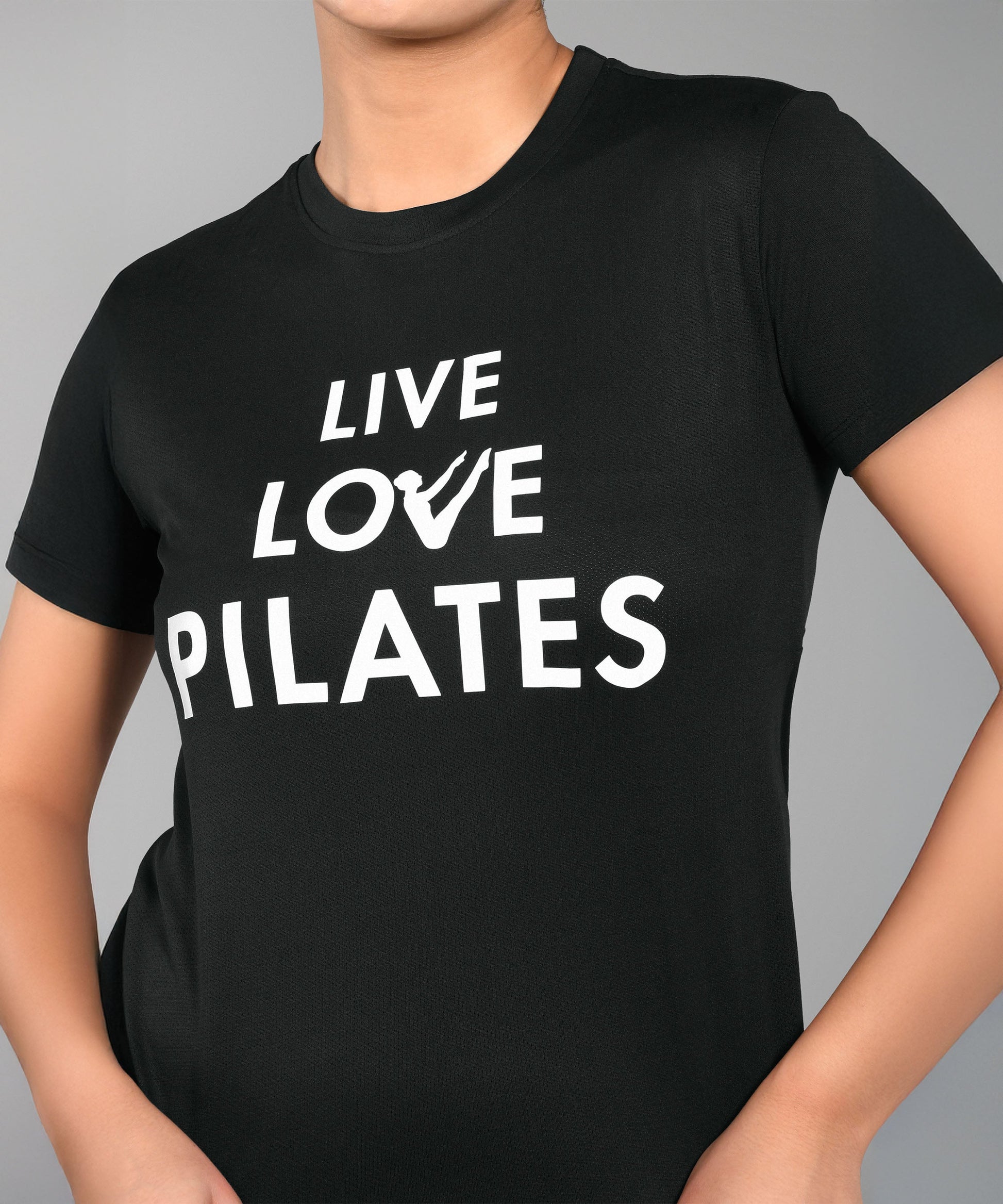 A person wears the Pilates Black T-shirt, a women's cotton modal tee with "LIVE LOVE PILATES" in bold white letters—ideal for any pilates enthusiast.