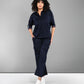 A woman with curly hair wears the Navy Blue Chic Set, featuring a navy shirt and track pants, standing against a gray background.