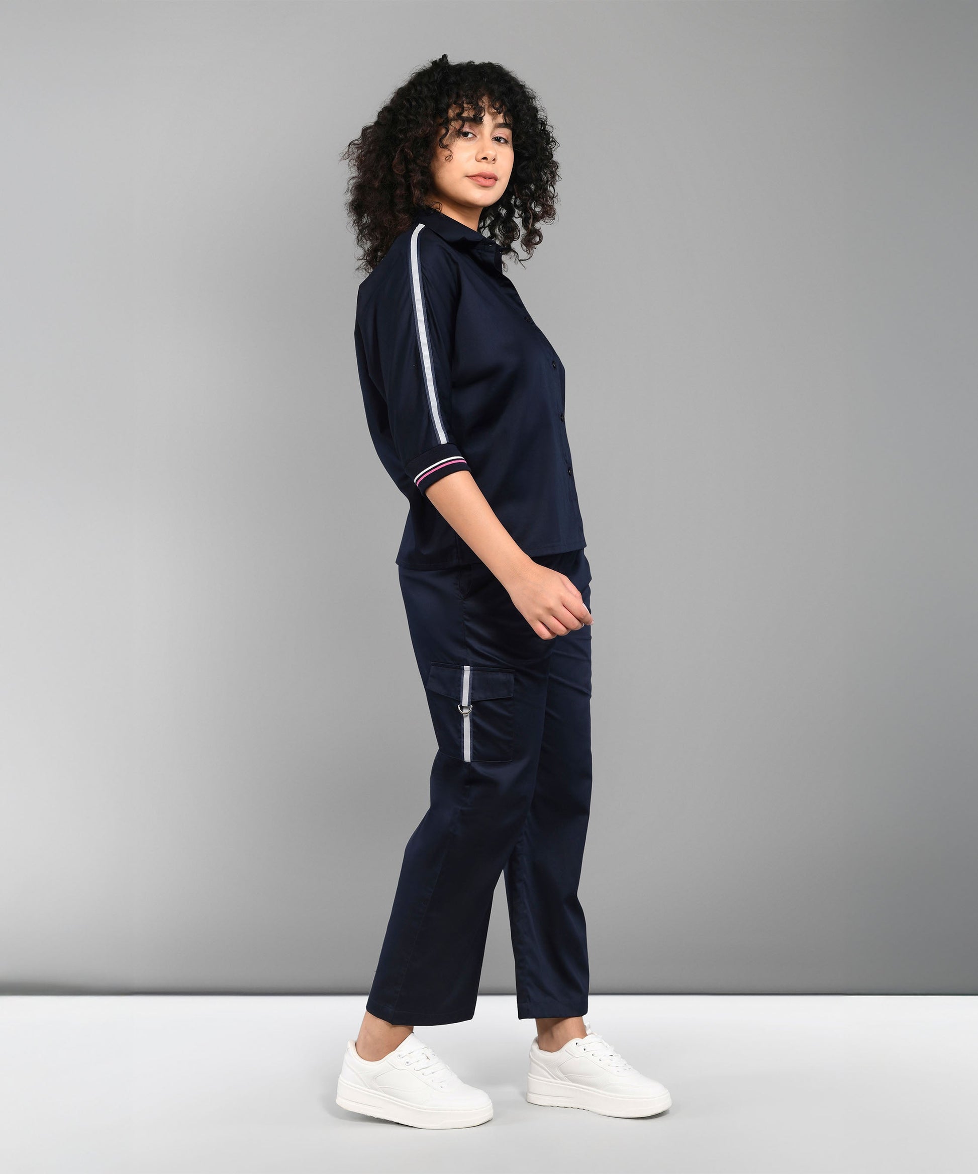 A woman models the Navy Blue Chic Set with white sneakers, posed sideways against a grey backdrop.