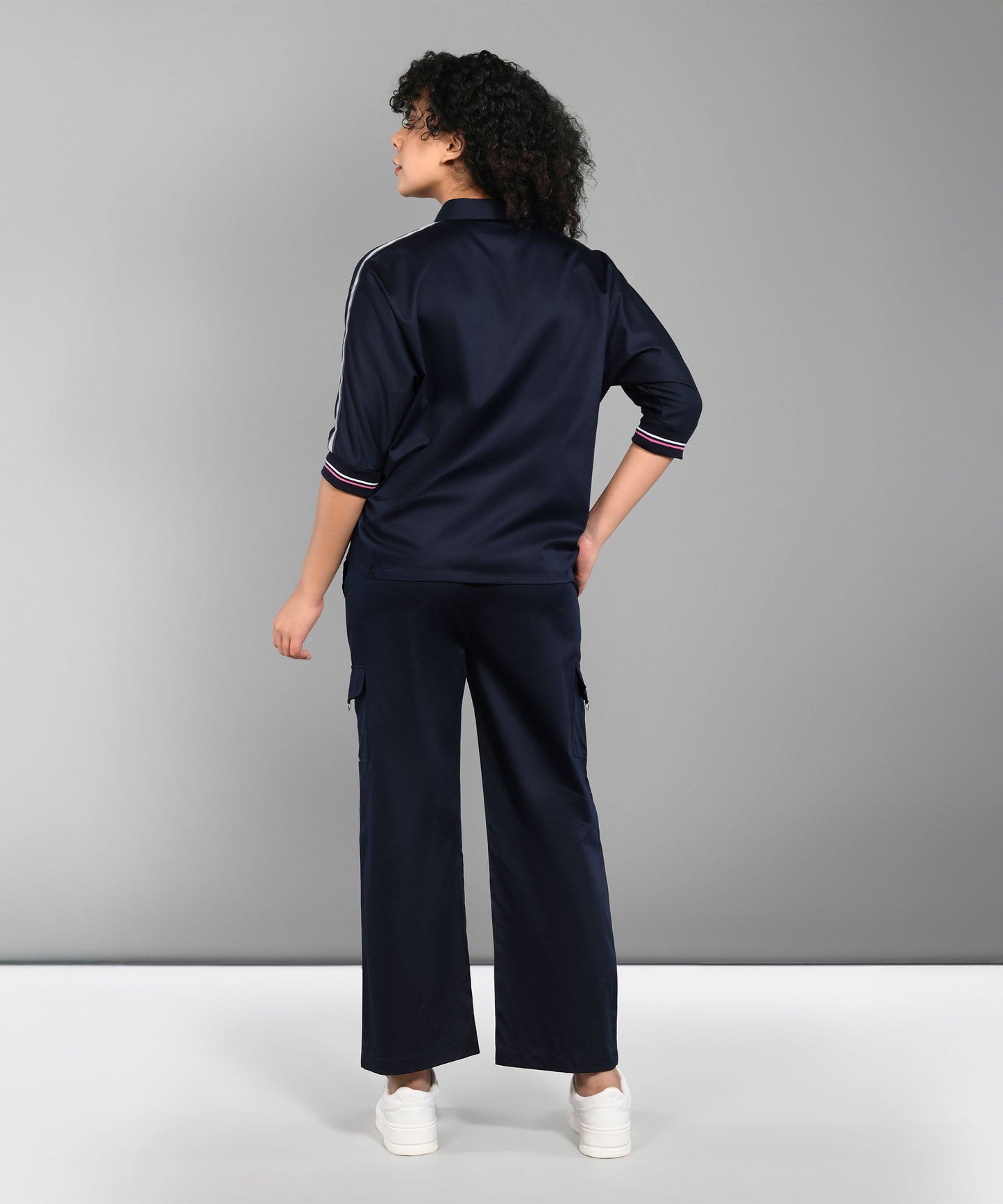 A person wearing the Navy Blue Chic Set with track pants and white sneakers stands facing away against a plain gray background.