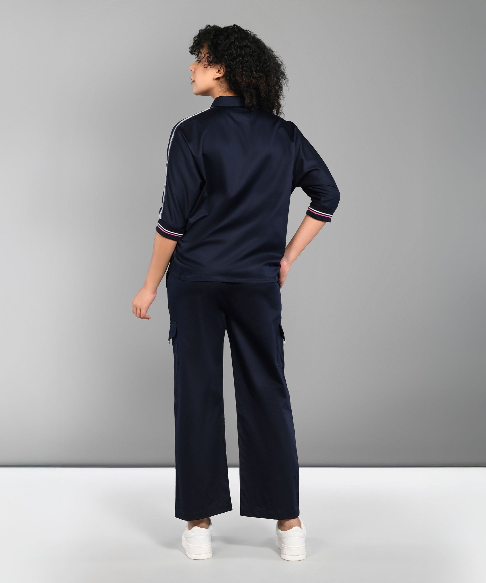 A person wearing the Navy Blue Chic Set with track pants and white sneakers stands facing away against a plain gray background.