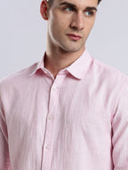 Detail of a structured spread collar on a pale pink textured linen button-down shirt.