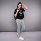 Woman wearing the 'Adore Your Core' Printed Tee with gray leggings, a backpack, and white sneakers poses and smiles.