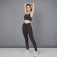Woman in Wine Leggings stretches with one arm raised, standing on a gray floor against a gray background.