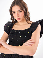 Female model wearing a sleeveless embroidered black romper from Stylera