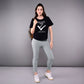 A woman stands confidently in our 'Adore Your Core' Printed Tee, pairing the black cotton-modal shirt with gray leggings and sneakers against a plain background.