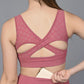 A woman wearing the Peony Pink Sports Bra with a cutout back holds a small wallet behind her. This moisture-wicking fitness top keeps you cool and comfortable during workouts.