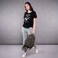 Woman in an 'Adore Your Core' printed tee and light leggings, holding a backpack, stands against a plain gray background.
