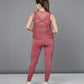 A woman stands facing away in the Peony Pink Netted Top, displaying its mesh design and honeycomb self pattern against a gray background.