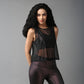 A woman with long curly hair models the Black Sheer Top and shiny leggings, posing against a plain gray background.