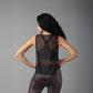 Woman models the Black Sheer Top, standing with hands on hips and facing away.