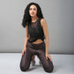 Woman with long curly hair kneeling on the floor, wearing a sexy Black Sheer Top and shiny dark leggings.