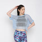A woman models the Blue Netted Top layered over a black sports bra and vibrant floral leggings, posing against a plain background for a chic, sporty vibe.