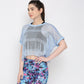 A woman showcases a sporty look in the Blue Netted Top and colorful floral leggings, posing against a plain white background.