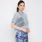 A woman wears a Blue Netted Top and colorful patterned pants, posing against a plain white background.