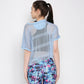 A woman faces away, wearing the Blue Netted Top layered over a striped shirt and stylish, colorful patterned leggings.