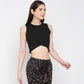 Woman wearing a Black Twisted Crop Top paired with black printed pants, standing against a plain light background.