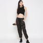 A woman poses against a white background wearing a Black Twisted Crop Top, printed joggers, and sneakers while holding a water bottle.