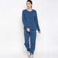 A woman wears the Atlantic Blue Active Duo, featuring a blue racerback top and cotton-modal joggers, styled with white athletic shoes against a plain background.