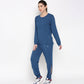 Woman wearing the Atlantic Blue Active Duo—racerback top and joggers made from buttery soft fabric—paired with white sneakers, stands against a plain background.