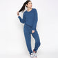 A woman in Atlantic Blue Active Duo loungewear—featuring soft Cotton Modal Joggers and a Blue Racer Back Top—stands against a white background, holding her ponytail and wearing sneakers for ultimate comfort.