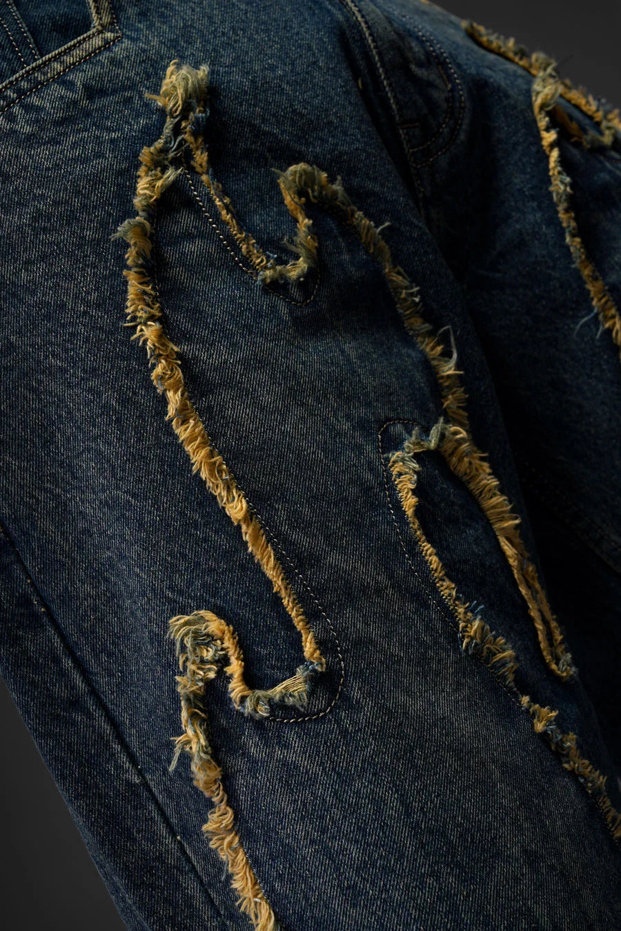 Front view of blue tribal denim jeans men India featuring relaxed baggy fit and raw-cut motifs.