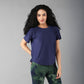 A woman with long curly hair wears the Functional - Blue Soft T Shirt, made from durable, comfortable materials, standing against a plain gray background.