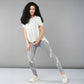 A woman poses confidently against a plain gray background wearing the Grey Top with Patched Legging, showcasing light, moisture-wicking fabric and bold patterns.