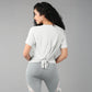 Woman in grey top with patched legging, featuring a knotted back t-shirt made from super soft fabric and patterned leggings, on a plain background.