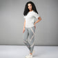 A woman showcases the Grey Top with Patched Legging, posing in a studio with a neutral gray background to highlight its super soft fabric and modern cross body design.
