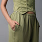 Model in the Olive Corset Crop - Top with Parachute Pants, posing with one hand in their pocket.