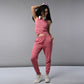 Woman wears a Pink Corset Crop-Top with Joggers, paired with headphones, posing confidently against a gray background.