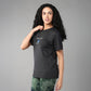 A woman with long curly hair embraces body positivity in the Positive Body Image T Shirt, featuring "Positive" text, styled with green tie-dye pants against a gray background.