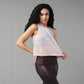 A woman with long curly hair poses against a gray background wearing the Powder Pink Sheer Top and shiny leggings.