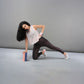 Woman wearing the Powder Pink Sheer Top balances on one knee with a yoga block, set against a plain gray background.