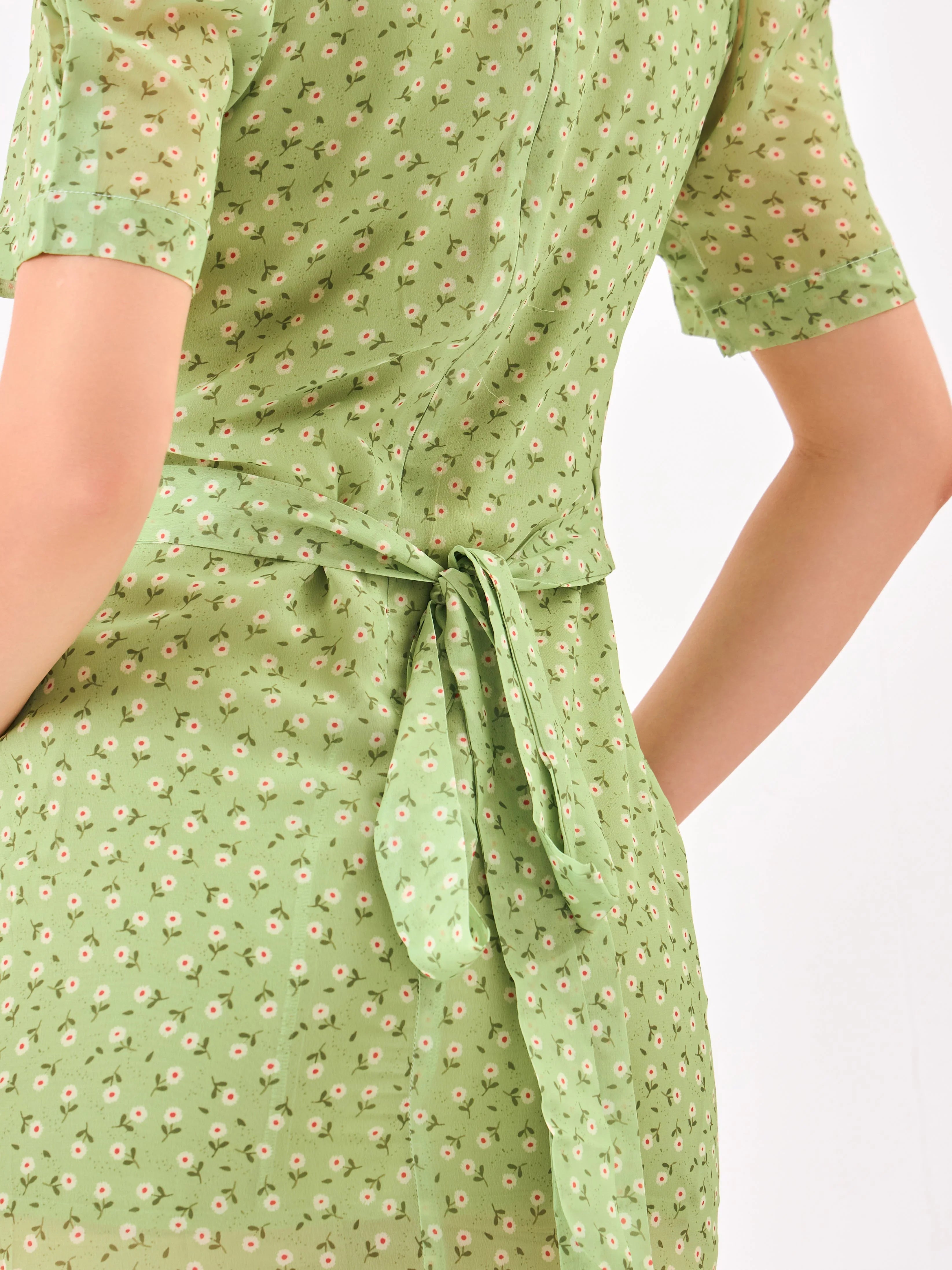 Female model wearing a green dress with a slit & back knot from Stylera