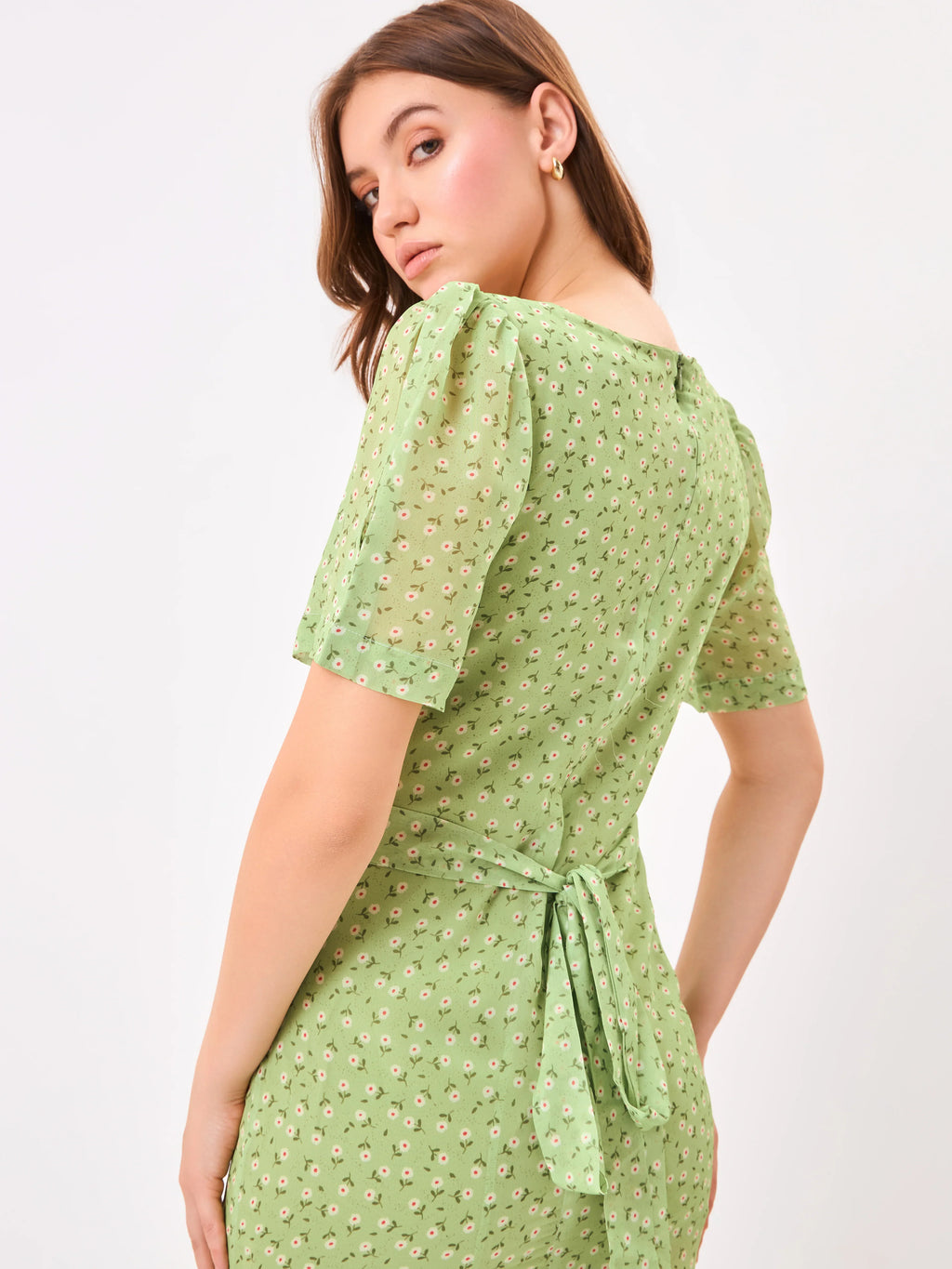 Female model wearing a green dress with a slit from Stylera, showcasing backside