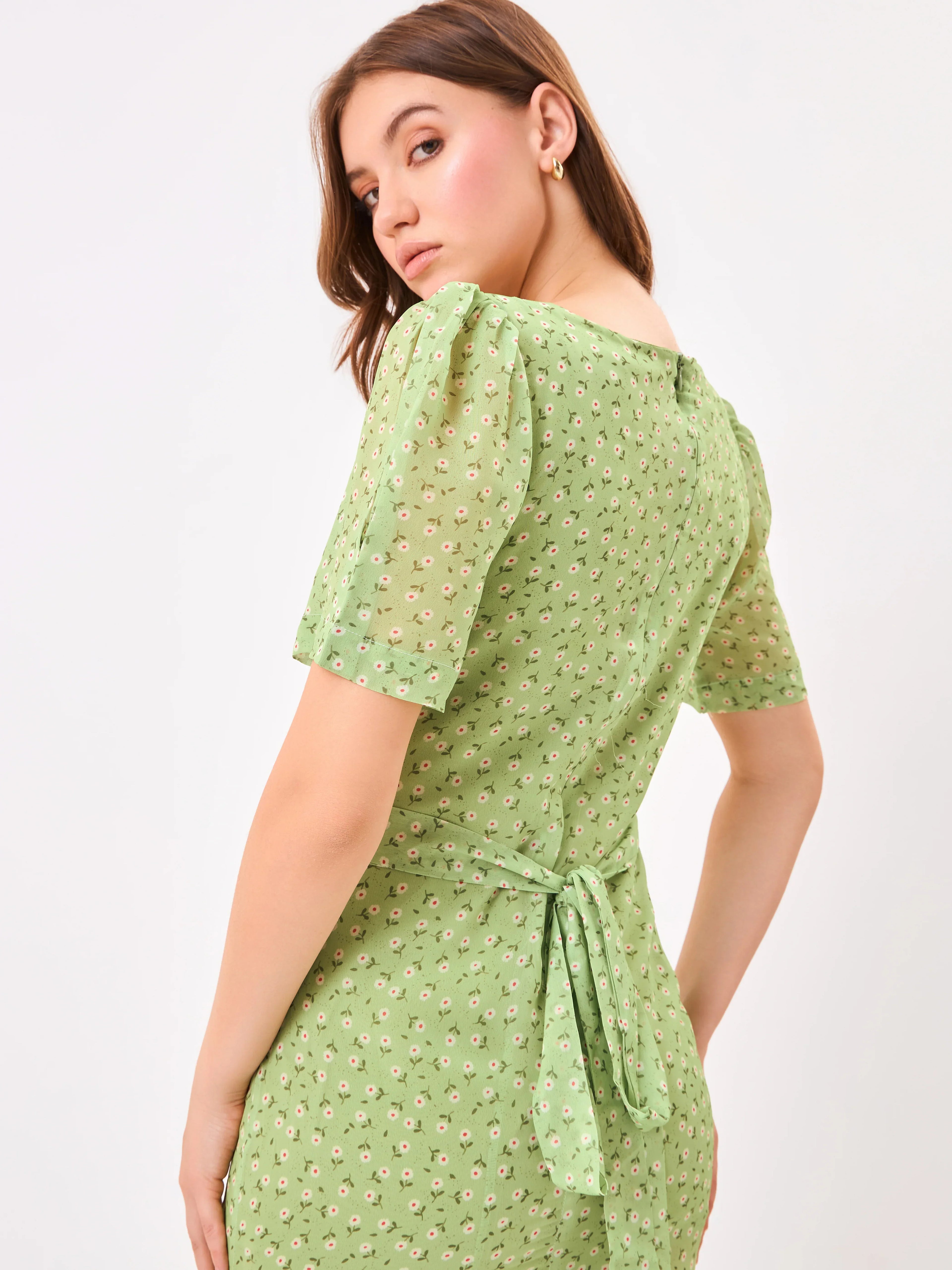 Female model wearing a green dress with a slit from Stylera, showcasing backside