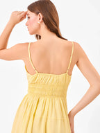 Female model wearing a yellow midi dress with elastic detail on back from Stylera