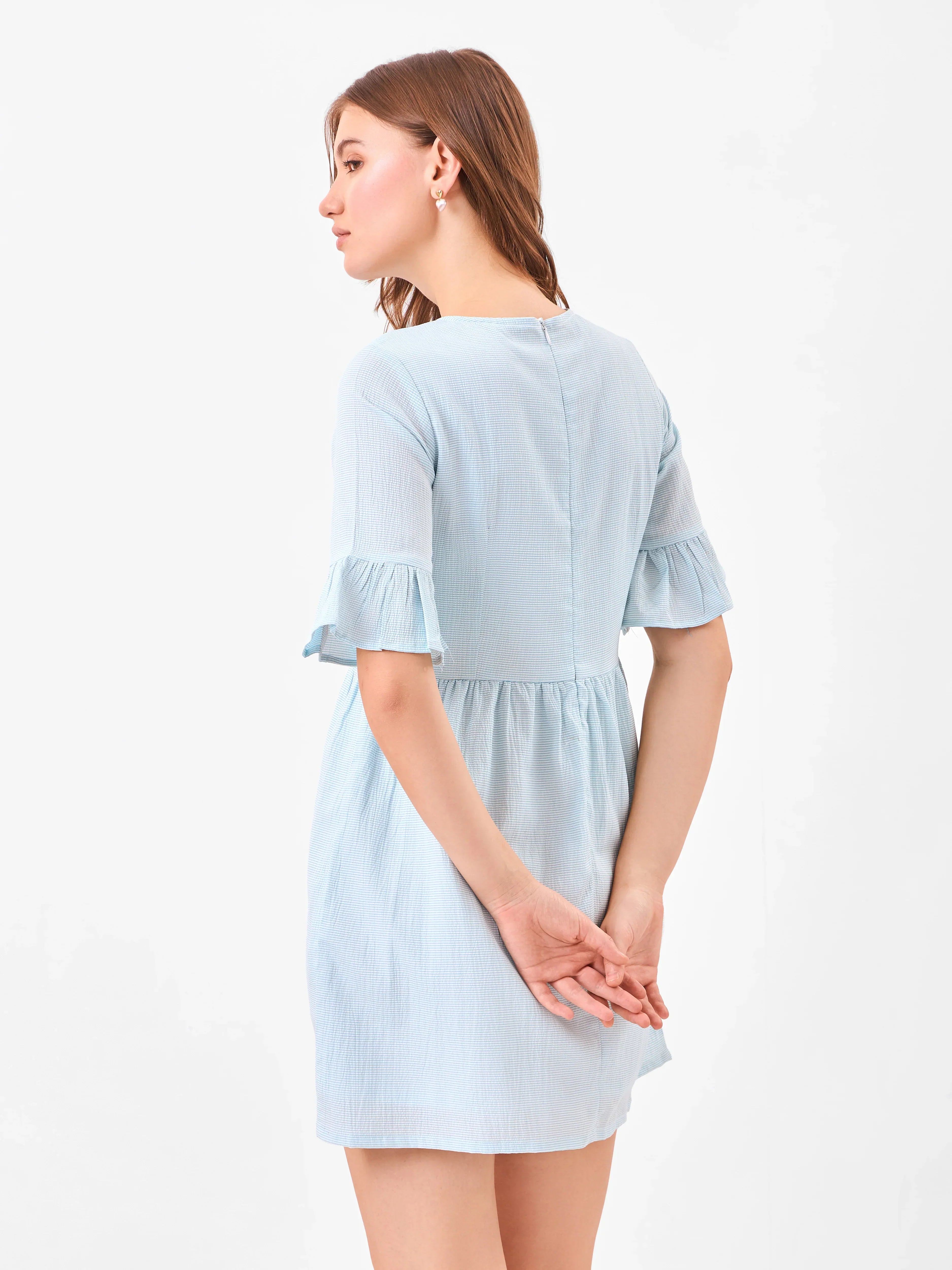 Female model wearing a light blue dress from Stylera, showcasing backside