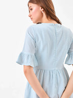Female model wearing a light blue dress with zipper on back from Stylera