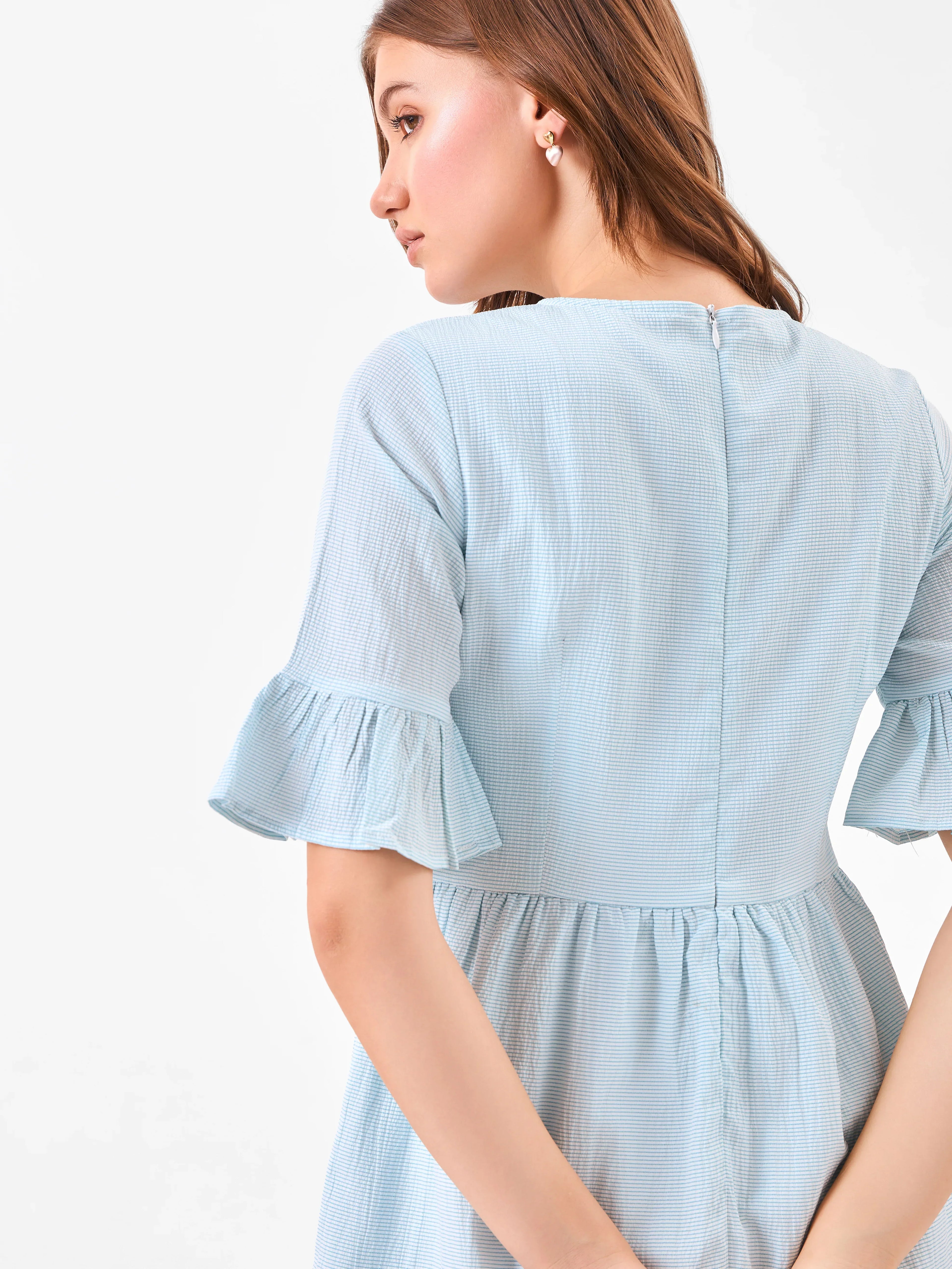 Female model wearing a light blue dress with zipper on back from Stylera