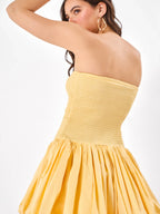 Female model wearing a yellow strapless dress with elastic fit from Stylera