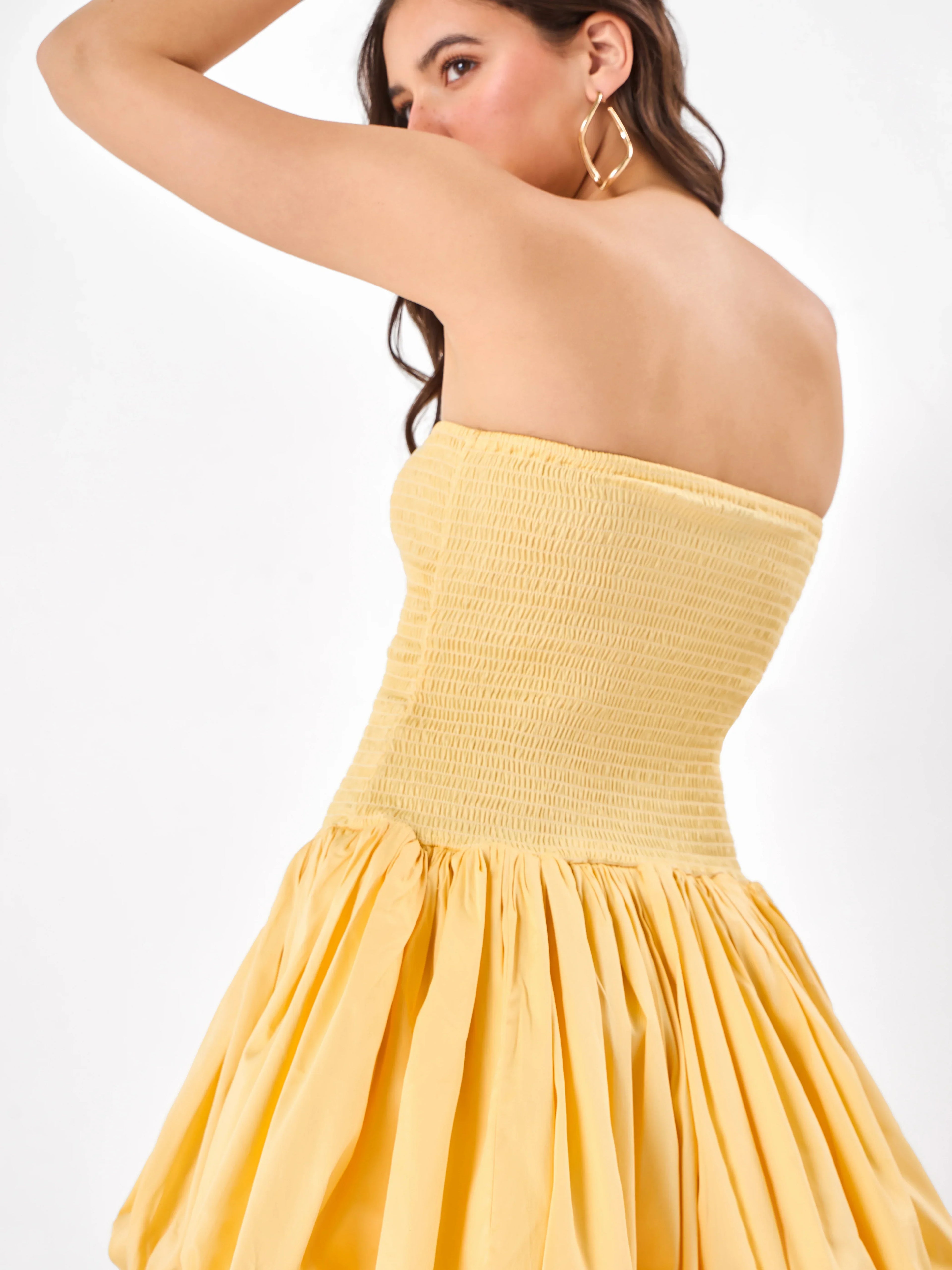 Female model wearing a yellow strapless dress with elastic fit from Stylera