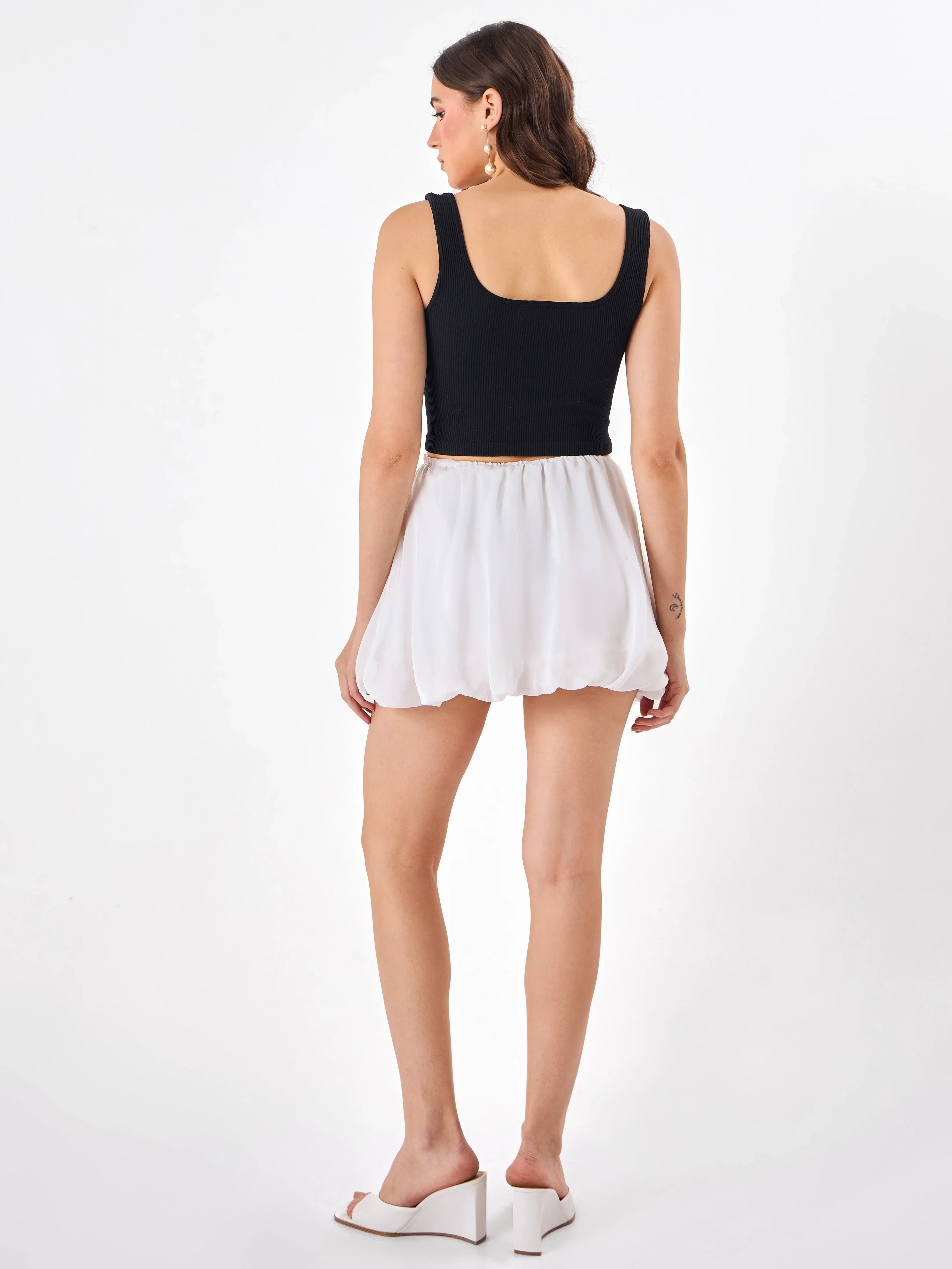 Female model wearing a white mini skirt  from Stylera, showcasing backside